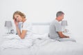 Annoyed couple sitting on different sides of bed having a dispute Royalty Free Stock Photo