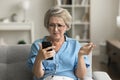 Annoyed frustrated retired woman in glasses getting problems with smartphone