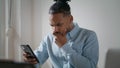 Annoyed guy using mobile phone at flat. Irritated man looking smartphone screen Royalty Free Stock Photo
