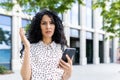 Annoyed Indian woman standing on the street with a phone in her hands, sad from bad news, outraged by a faulty Royalty Free Stock Photo