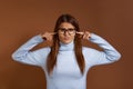Annoyed, irritated, angry young caucasian woman wearing glasses and light blue sweater plugs her ears with fingers, can`t stand Royalty Free Stock Photo