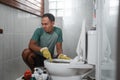 an annoyed male wearing gloves brushing the dirty toilet