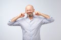 Annoyed mature man plugging ears with fingers