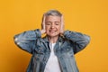 Annoyed Middle Aged Woman Covering Ears In Stress, Standing Over Yellow Background Royalty Free Stock Photo