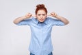 Annoyed redhead woman wearing blue shirt irritated by loud noise covering ears and grimacing in pain Royalty Free Stock Photo