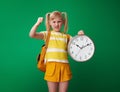 Annoyed school girl with clock isolated on green background