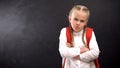 Annoyed schoolgirl with crossed hands looking at camera, education problems