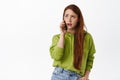 Annoyed teen girl with red hair talks on phone, roll eyes bothered and irritated by boring conversation, standing Royalty Free Stock Photo