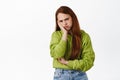 Annoyed teen redhead girl sulking, looking bothered and upset, pouting at folks, lean on hand and frowning displeased Royalty Free Stock Photo