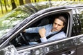 Annoyed tired young man is riding driving car. Businessman is late for meeting. Driver brunette in grey suit stuck in traffic jam Royalty Free Stock Photo