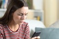 Annoyed woman checking smart phone at home