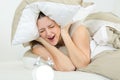 annoyed woman covering ears with pillow bed Royalty Free Stock Photo