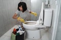 an annoyed woman wearing gloves brushing the dirty toilet