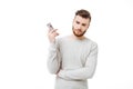 Annoyed young man holding smartphone far from his ear. Angry man doesn`t want to listen talking on the phone isolated Royalty Free Stock Photo