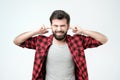 Annoyed young man plugging ears with hands. Studio shoot