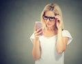 Annoyed upset woman in glasses looking at her cell phone with frustration Royalty Free Stock Photo