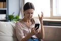 Annoyed young woman looking at mobile phone screen. Royalty Free Stock Photo