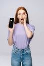 Annoyed young woman wearing stylish clothes holding cell phone with black empty mobile screen Royalty Free Stock Photo