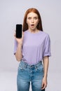 Annoyed young woman wearing stylish clothes holding cell phone with black empty mobile screen Royalty Free Stock Photo