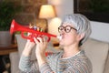 Annoying senior woman playing plastic trumpet Royalty Free Stock Photo