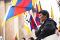 Profile of a Tibetan man arms crossed in front of flags of Tibet