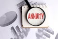 Annuity text under magnifying glass on notepad with financial graphs and charts in background Royalty Free Stock Photo