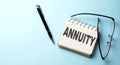 ANNUITY text is written on a notepad on the blue background