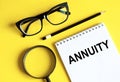 ANNUITY text is written on notepad on the yellow background