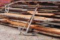 Old rusted anchor leaning against a pile of lumber to be used to repair ships