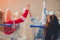 Anonymous best friends holding hands and riding shopping trolleys Royalty Free Stock Photo