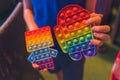 Anonymous child hold in his hands sensory toy pop it and shows it in front of himself.Rainbow color.Antistress toy for