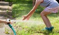 Anonymous child, school age girl playing with a water stream from a garden hose, hands catching water stream. Summer, summertime