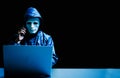 Obscured dark face using laptop computer for cyber attack and calling on cellphone, Data thief, Royalty Free Stock Photo