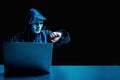 Anonymous computer hacker in white mask and hoodie. Obscured dark face using laptop computer for cyber attack and checking time , Royalty Free Stock Photo