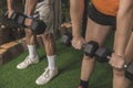 An anonymous couple does dumbbell Romanian deadlifts on the artificial grass mat of a home gym. Closeup shot