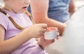 Anonymous elementary school age child girl eating ice cream from a small white blank paper cup with a spoon, closeup, detail, one Royalty Free Stock Photo