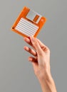 Unrecognizable woman displaying vintage floppy disk in light against gray backdrop Royalty Free Stock Photo