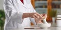 Anonymous female pharmacist in white robe grinding medical ingredient and using mortar and pestle, Generative AI Royalty Free Stock Photo