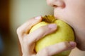 Anonymous girl eating delicious yellow apple at home