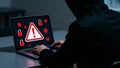 Anonymous Hacker in Hoodie Attacking Laptop with Malware and Ransomware Alert Royalty Free Stock Photo