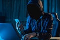 Anonymous hacker programmer uses a laptop to hack the system in the dark. Concept of cybercrime and hacking database