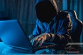 Anonymous hacker programmer uses a laptop to hack the system in the dark. Concept of cybercrime and hacking database Royalty Free Stock Photo