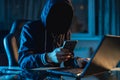 Anonymous hacker programmer uses a laptop to hack the system in the dark. Concept of cybercrime and hacking database Royalty Free Stock Photo