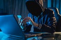 Anonymous hacker programmer uses a laptop to hack the system in the dark. Concept of cybercrime and hacking database Royalty Free Stock Photo