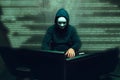 Anonymous hacker wearing face mask working on computer in dark room Royalty Free Stock Photo