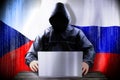 Anonymous hacker working on a laptop, flags of Czech Republic and Russia