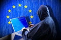 Anonymous hooded hacker, flag of European Union, binary code - cyber attack concept