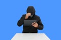 Anonymous hooded hackers hacking data of tablet isolated on blue background. Image with Clipping path