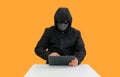 Anonymous hooded hackers hacking data of tablet on orange background. Image with Clipping path