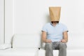 Anonymous inexpressive man with head hidden in a paper bag.